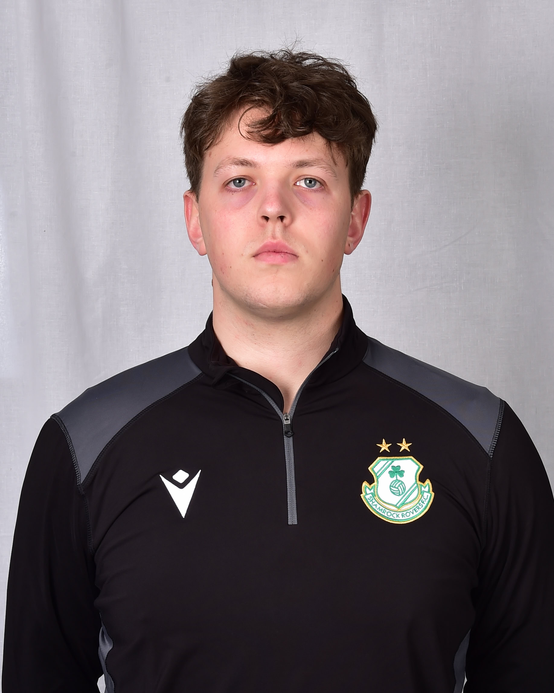 Shamrock Rovers player in team kit with club crest, facing forward.