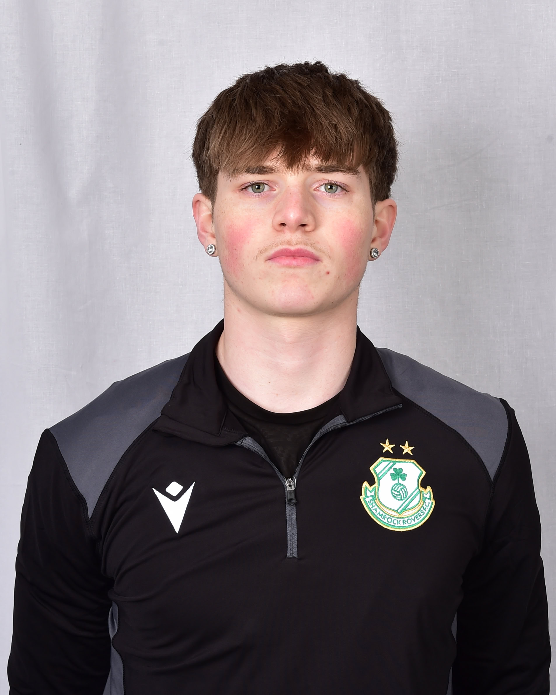 Shamrock Rovers football player in team kit, facing forward, on grey background.