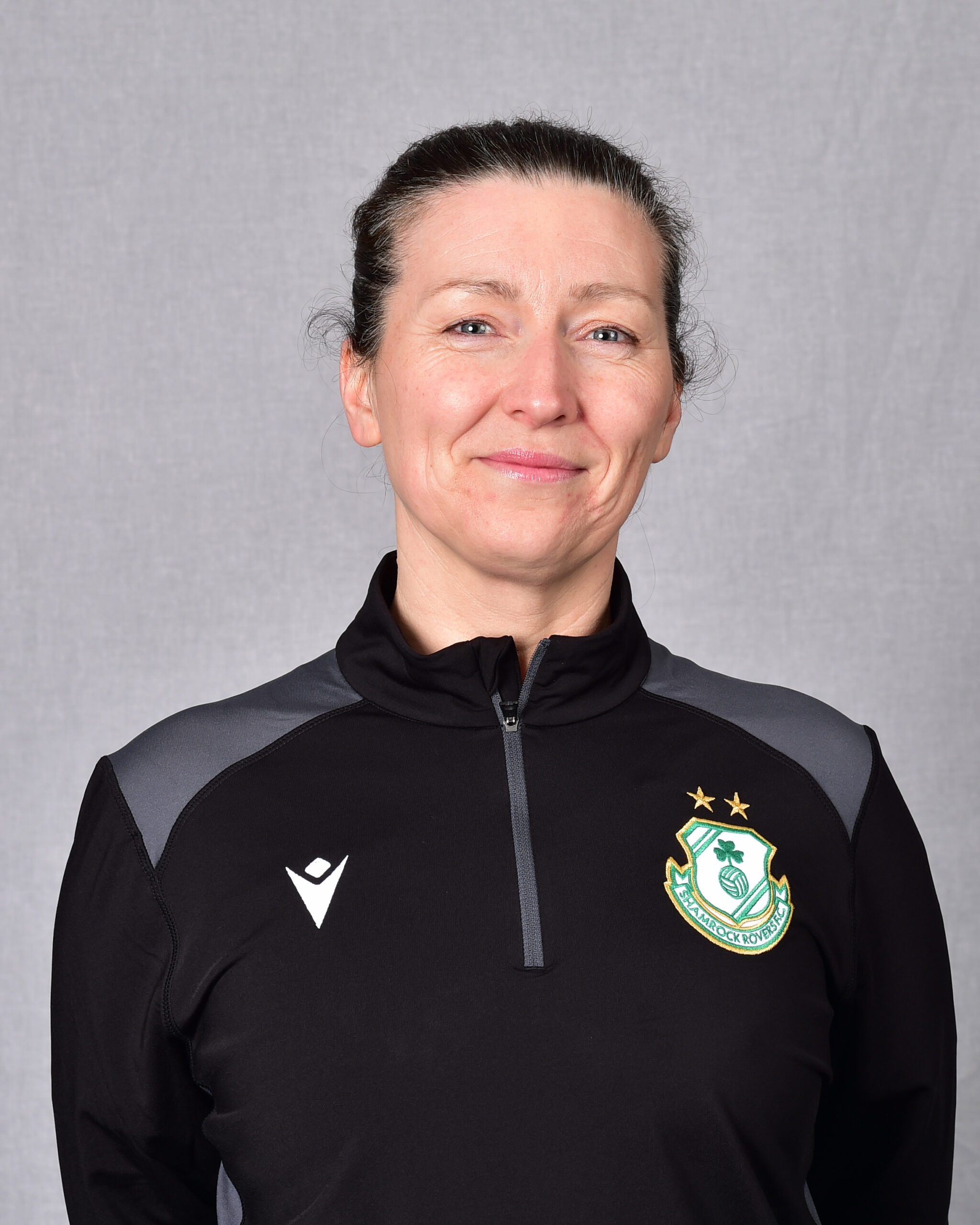 Female Shamrock Rovers player in team jersey smiling at camera.