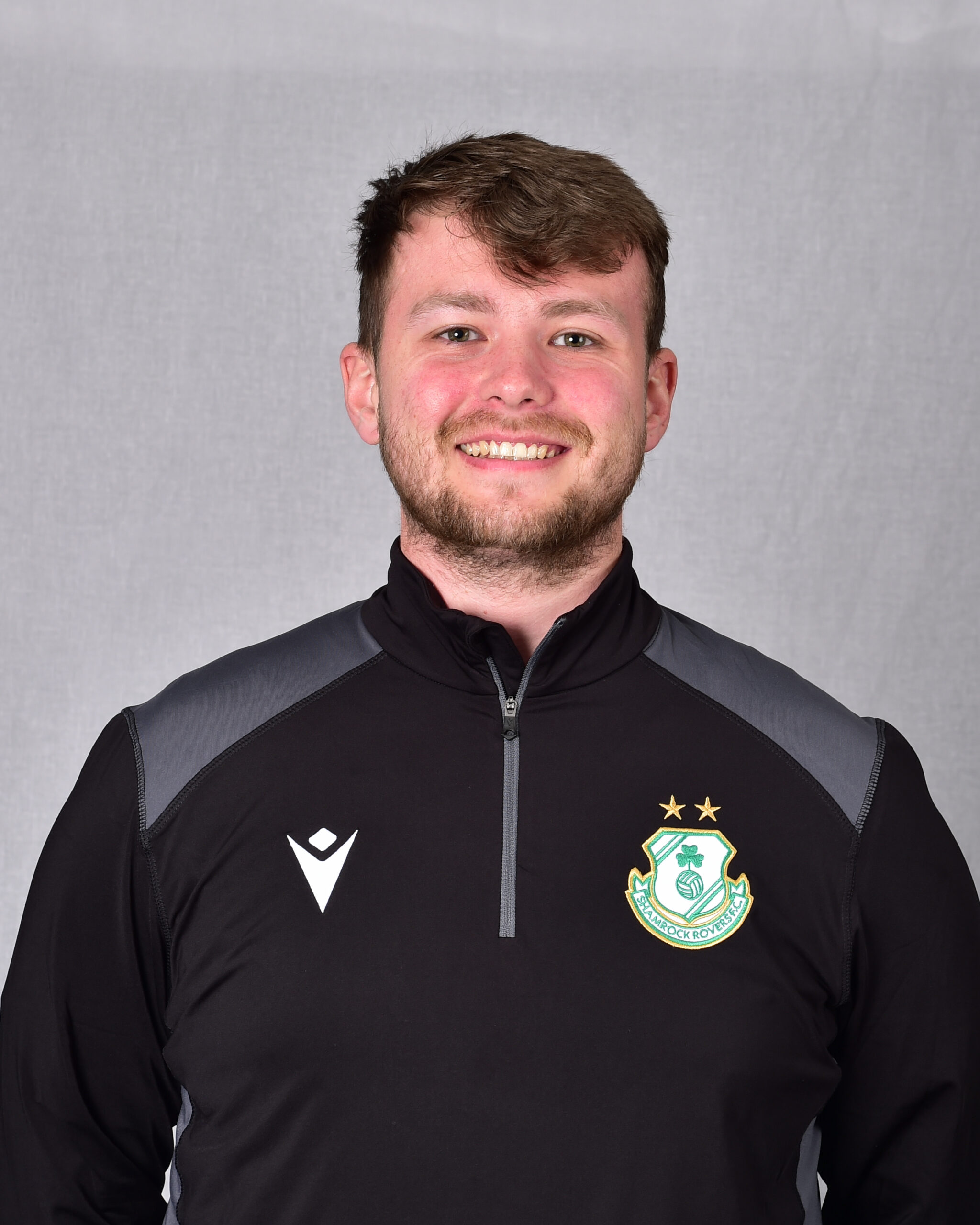 Shamrock Rovers football player in team kit smiling at camera.