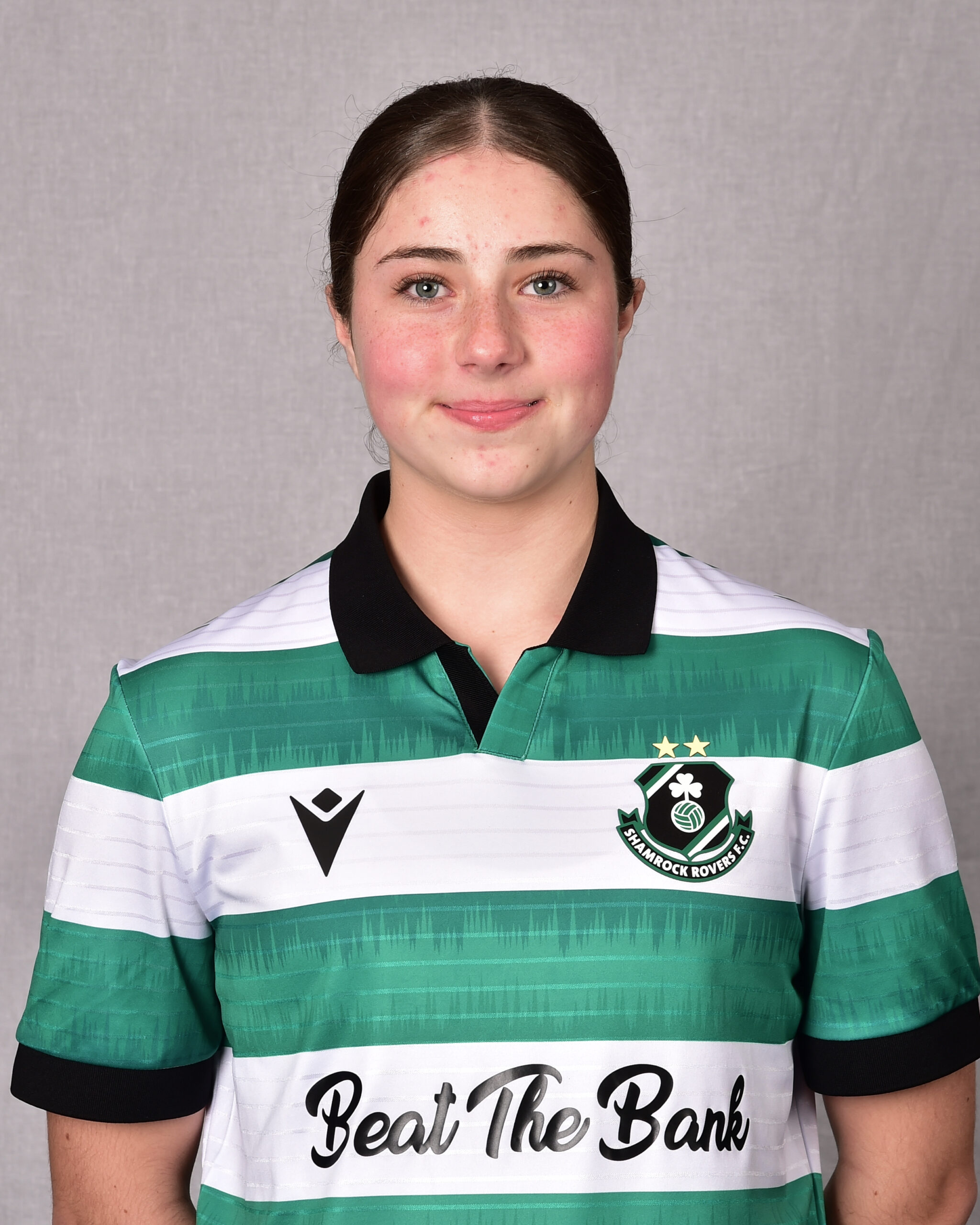 Female Shamrock Rovers player in team jersey smiling at camera.
