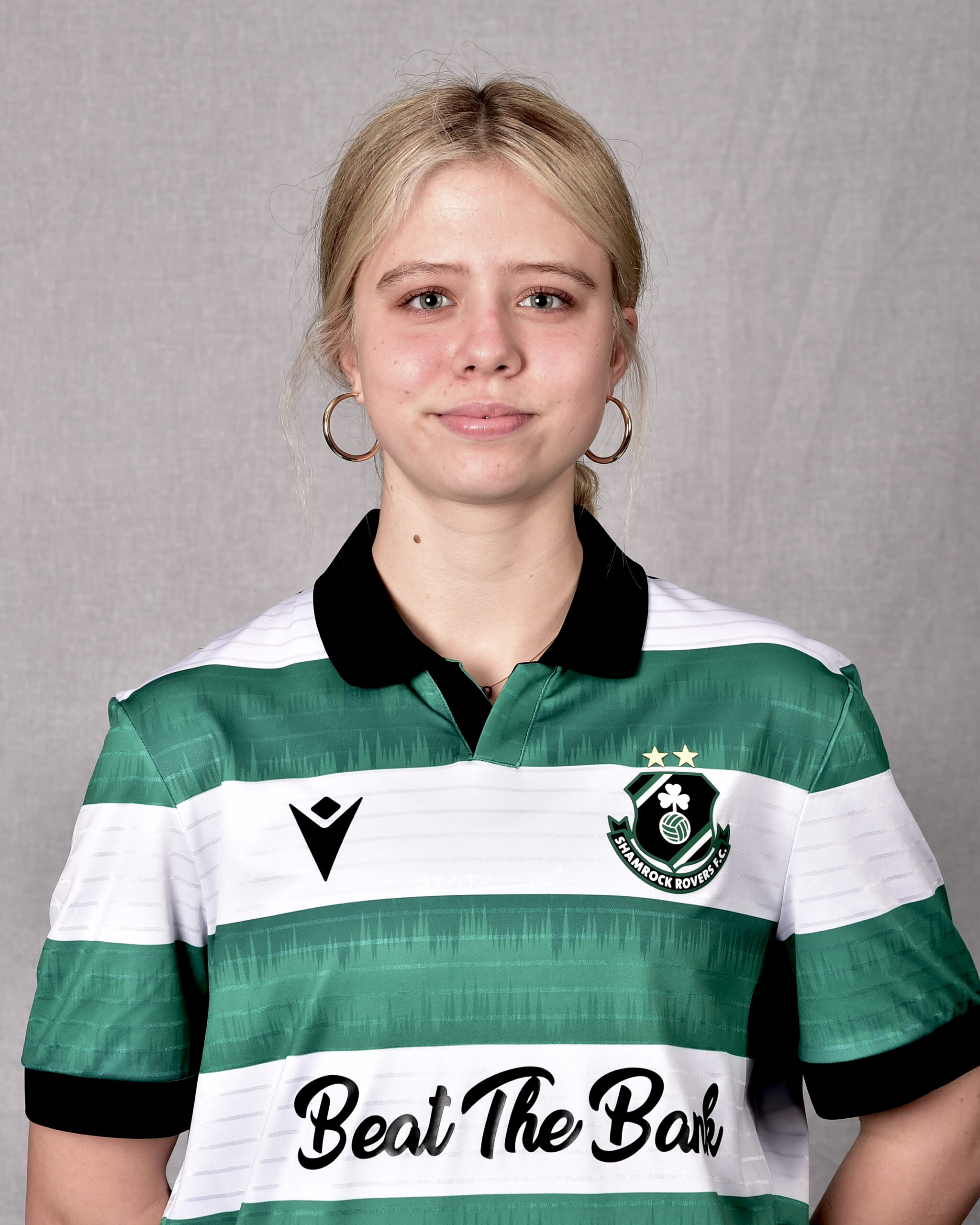 Female Shamrock Rovers player in green and white jersey, smiling.