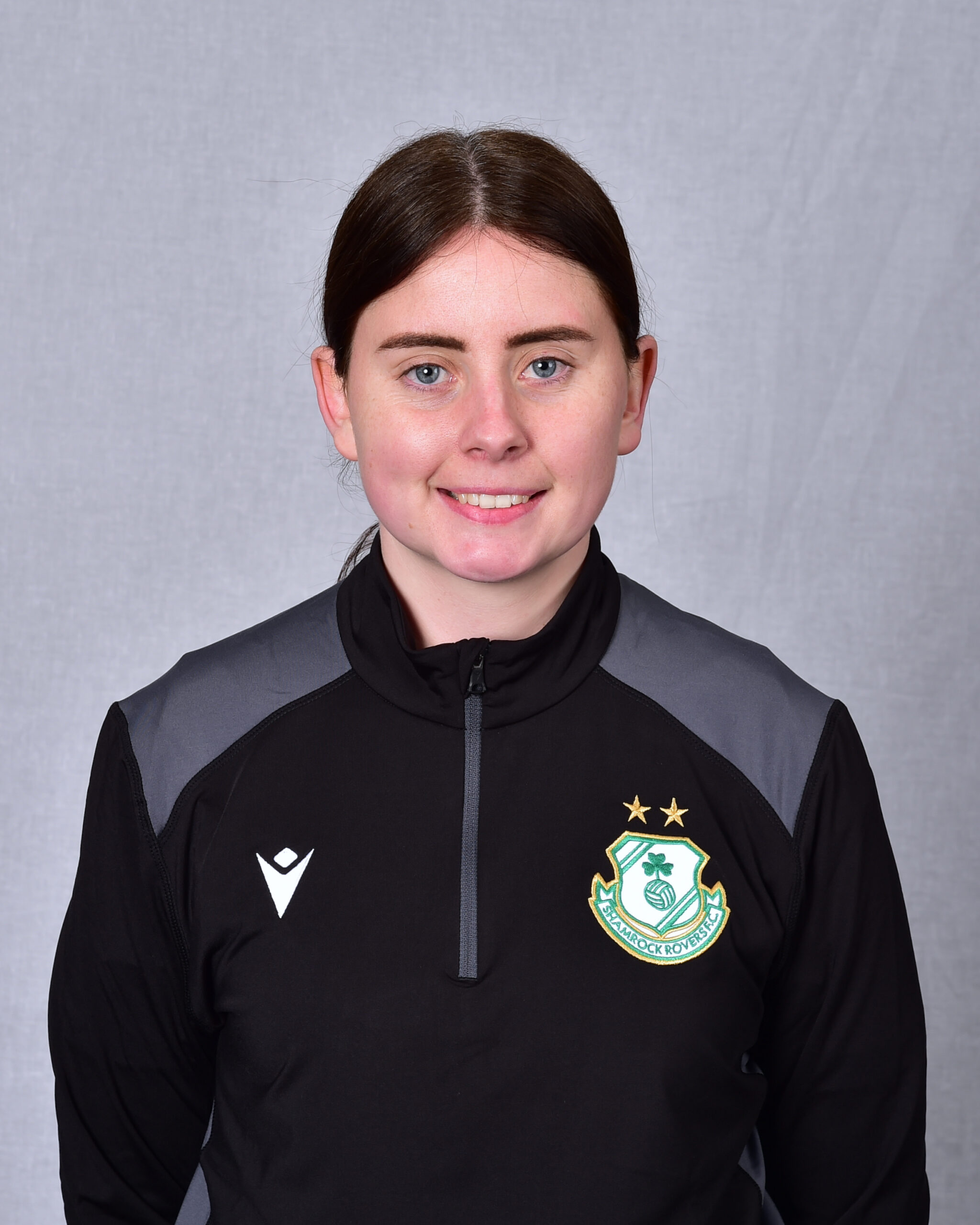Female Shamrock Rovers player in team kit smiling at camera.