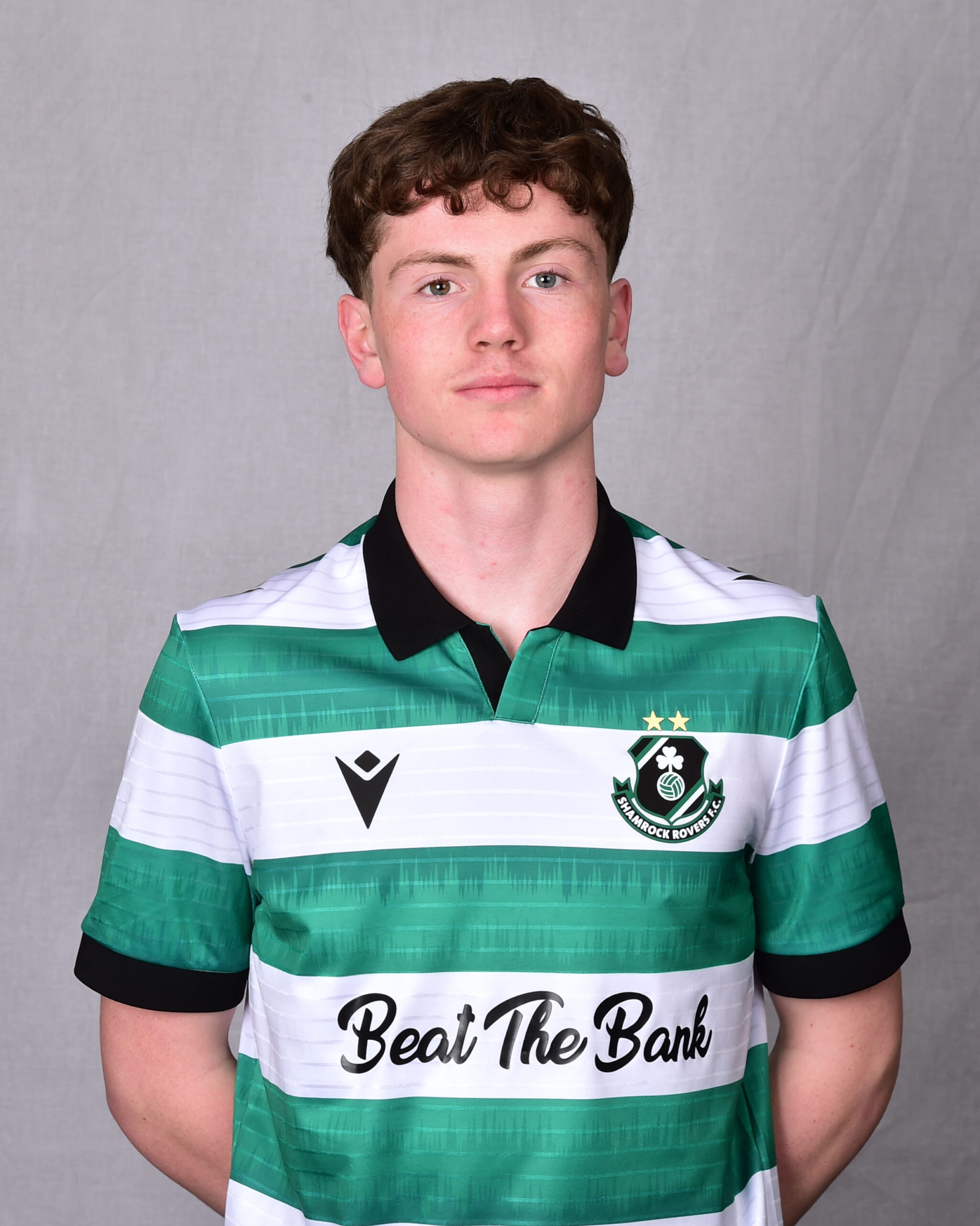 Young Shamrock Rovers footballer in green and white striped kit, facing camera.