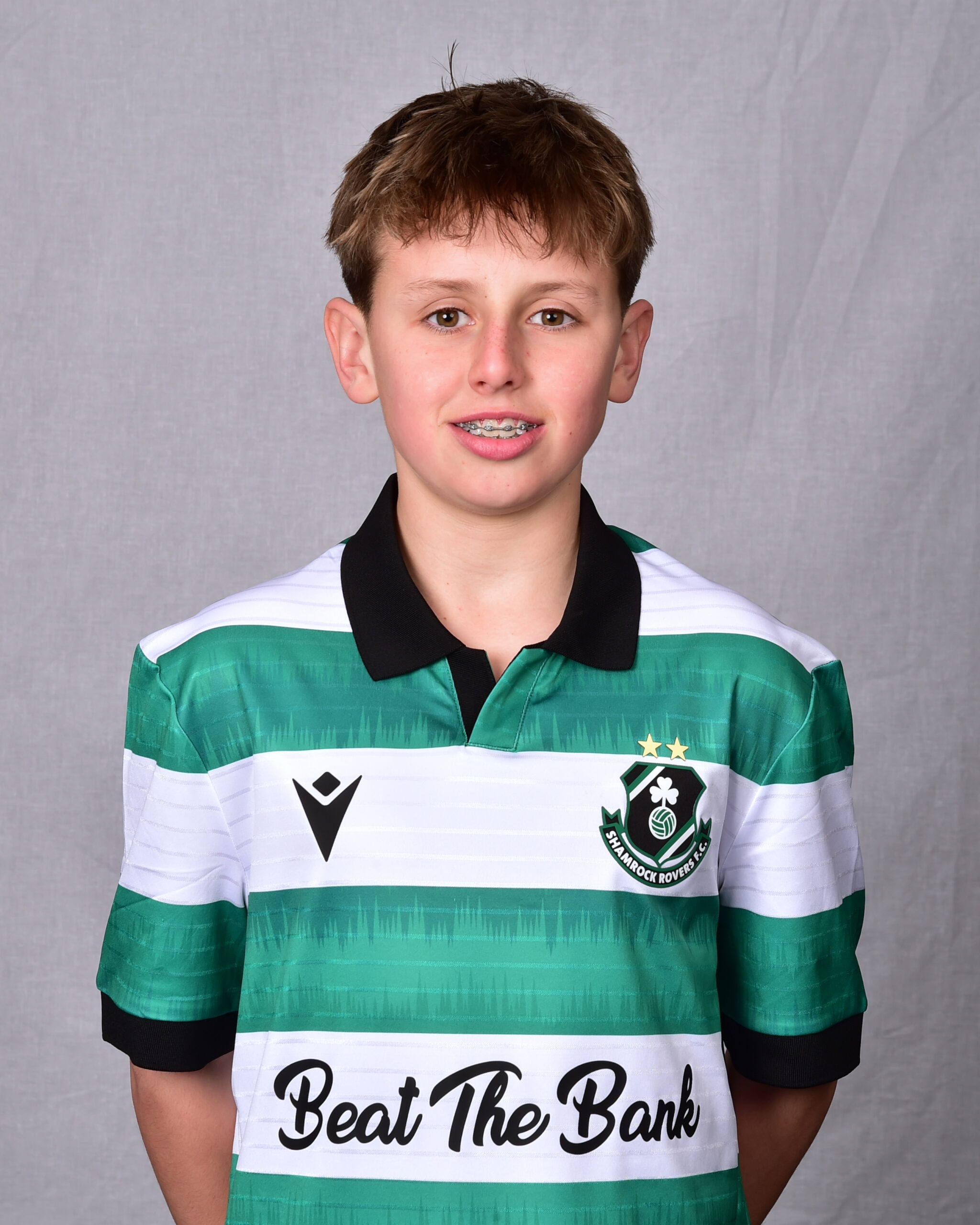 Young Shamrock Rovers player in team jersey, smiling for photo.