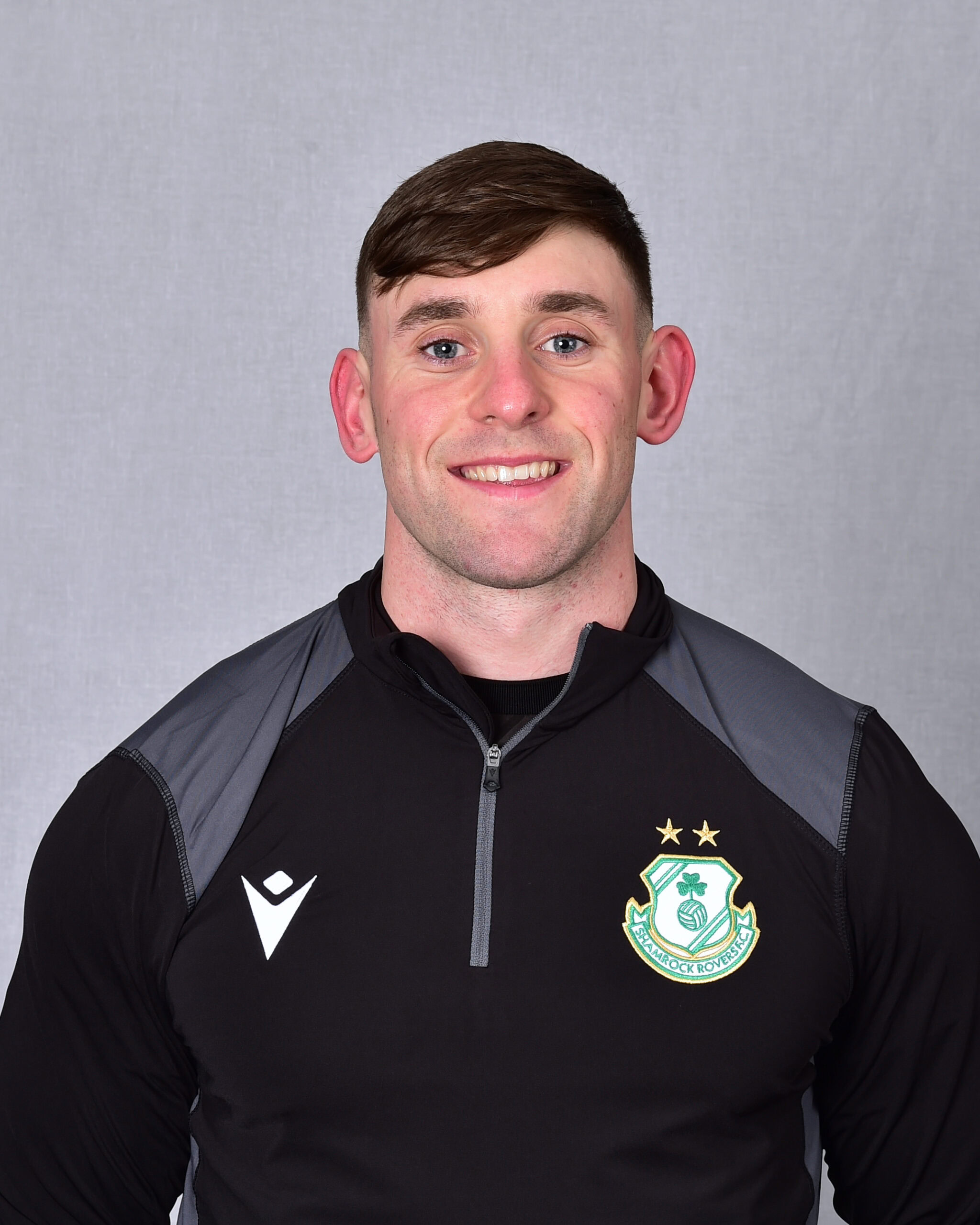 Shamrock Rovers football player in team kit with club crest and stars.