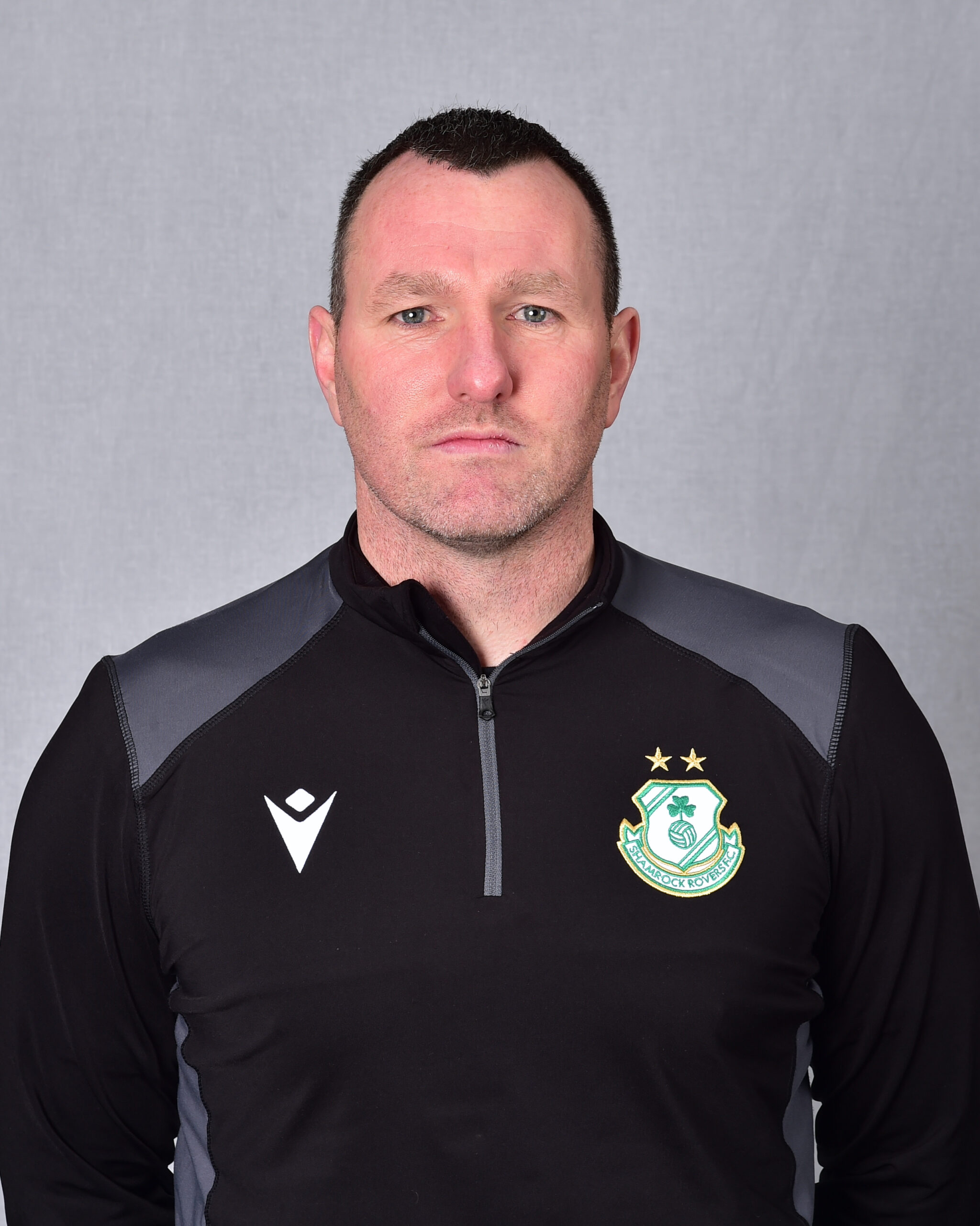 Shamrock Rovers coach in team training gear, standing against a grey background.
