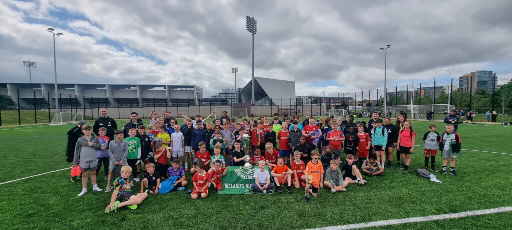 Shamrock Rovers players and children pose together on the football pitch.