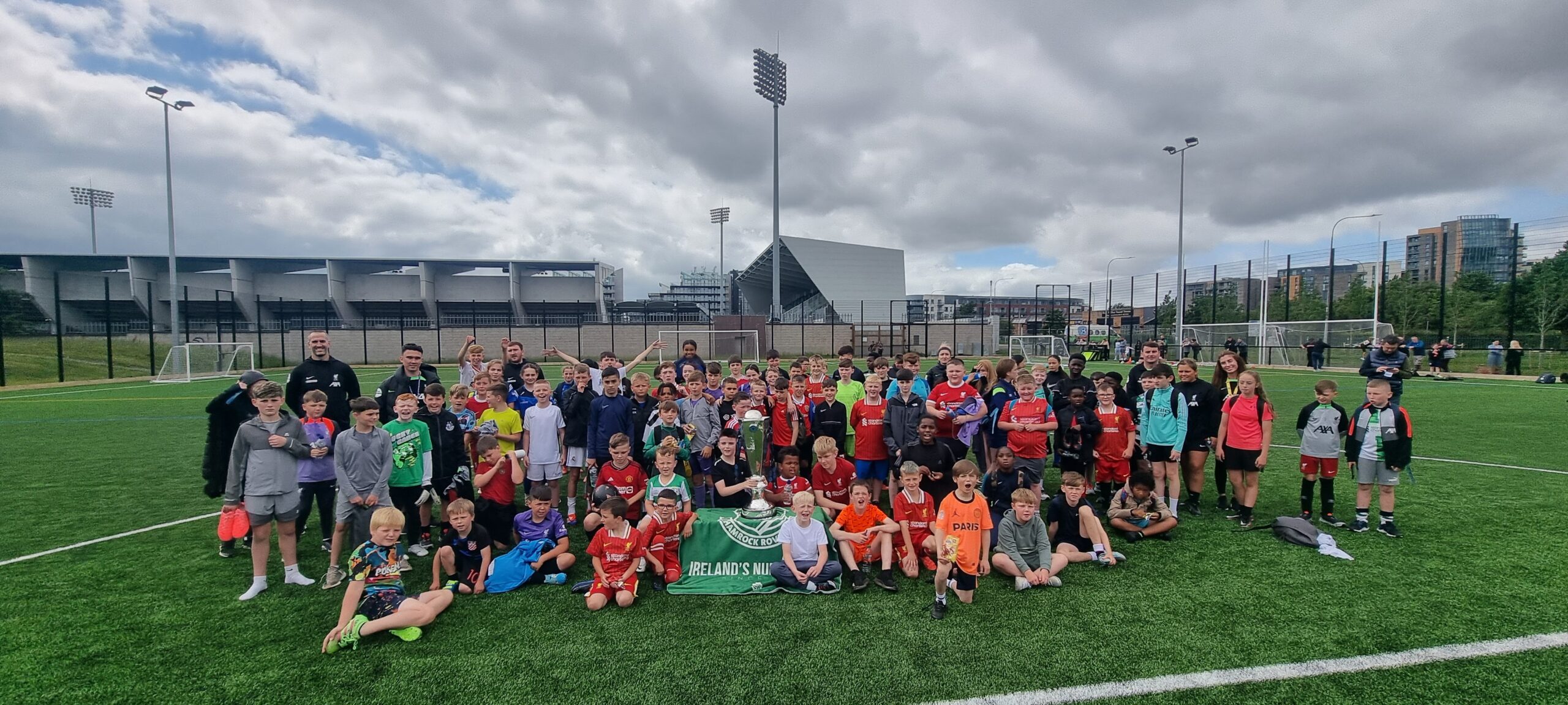 Shamrock Rovers players and children pose together on the football pitch.