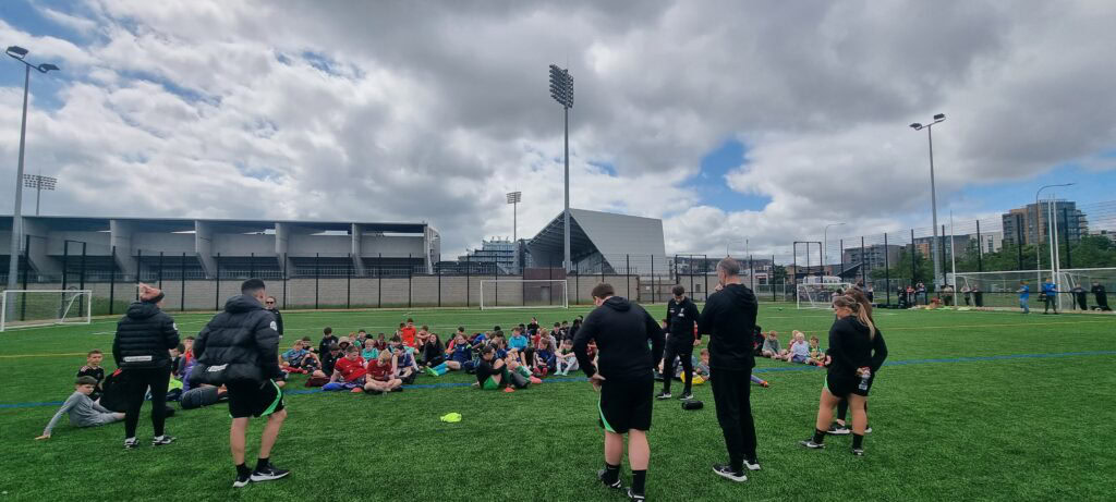 Shamrock Rovers youth players training on the football pitch with coaches and staff.