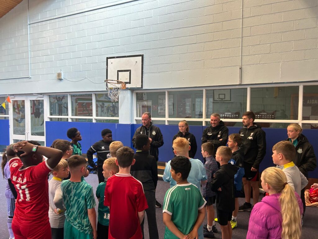 Shamrock Rovers players and children during youth training session in indoor gym.