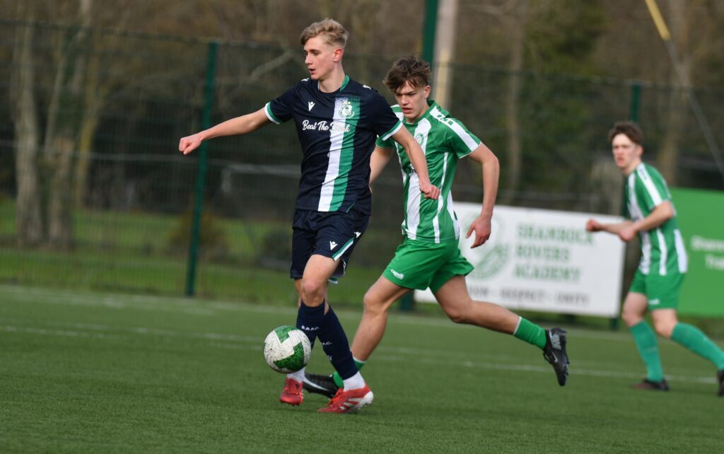 Two young footballers competing for the ball during a Shamrock Rovers youth match.