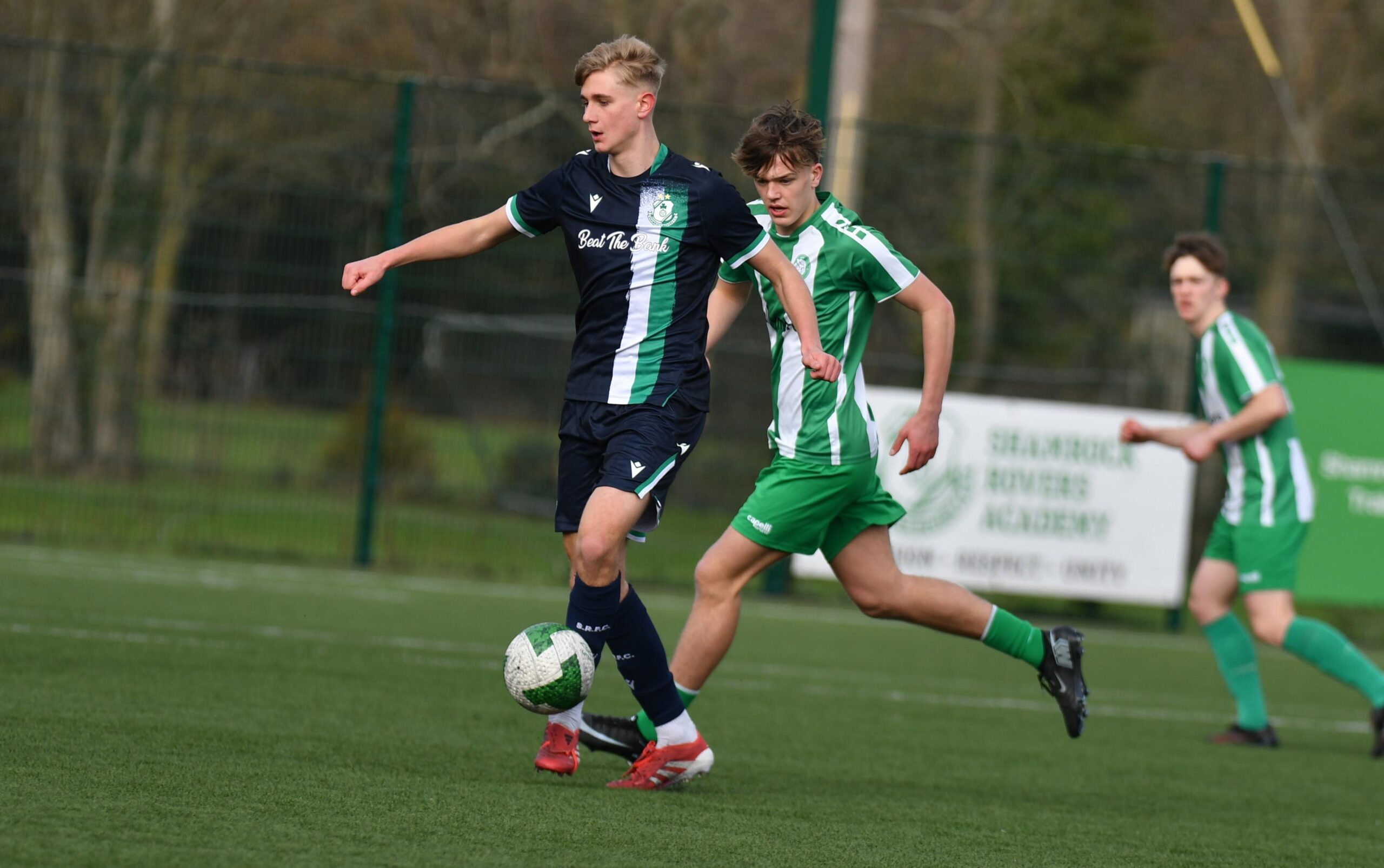Two young footballers competing for the ball during a Shamrock Rovers youth match.