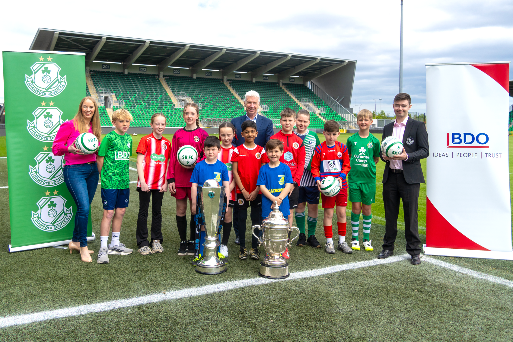 Young football players at Shamrock Rovers summer camp with coaches and trophies.