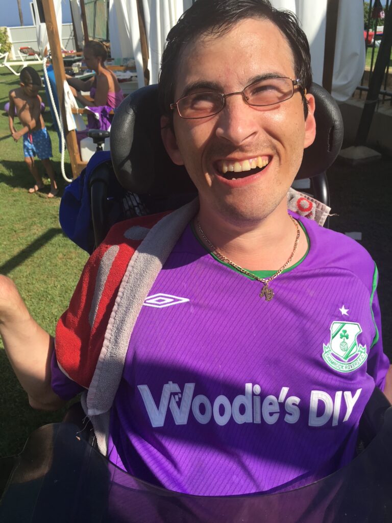 Shamrock Rovers fan in wheelchair wearing team jersey at a match.