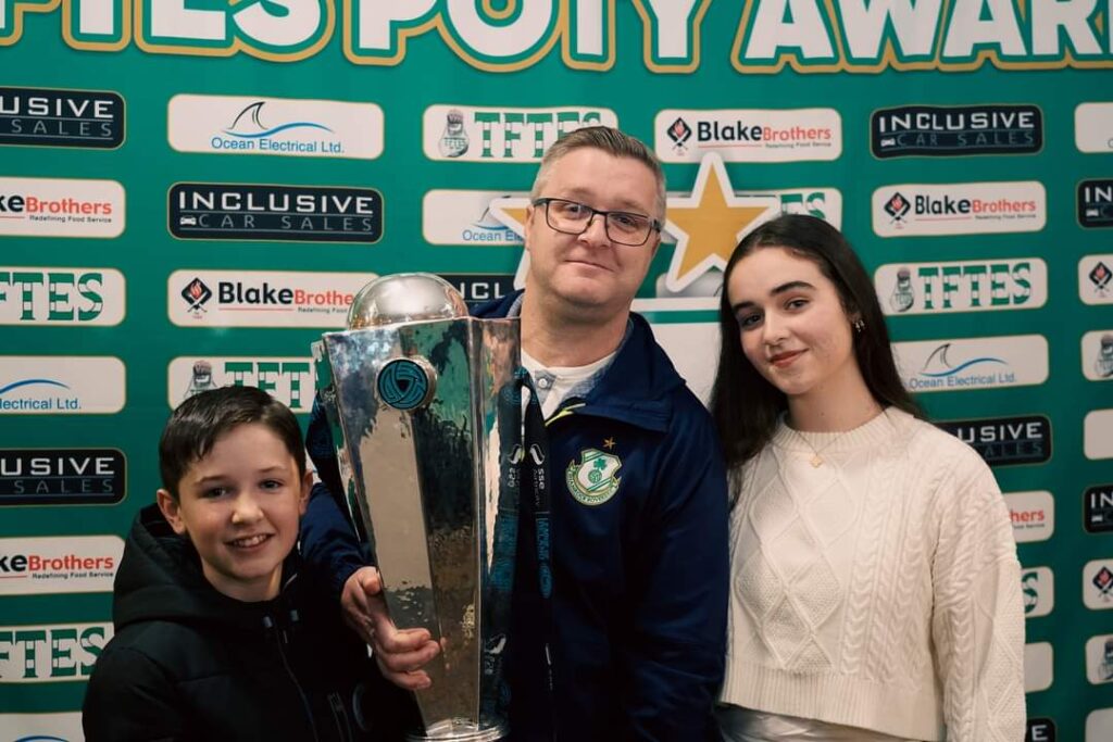 Shamrock Rovers players and staff holding the trophy at an awards event.