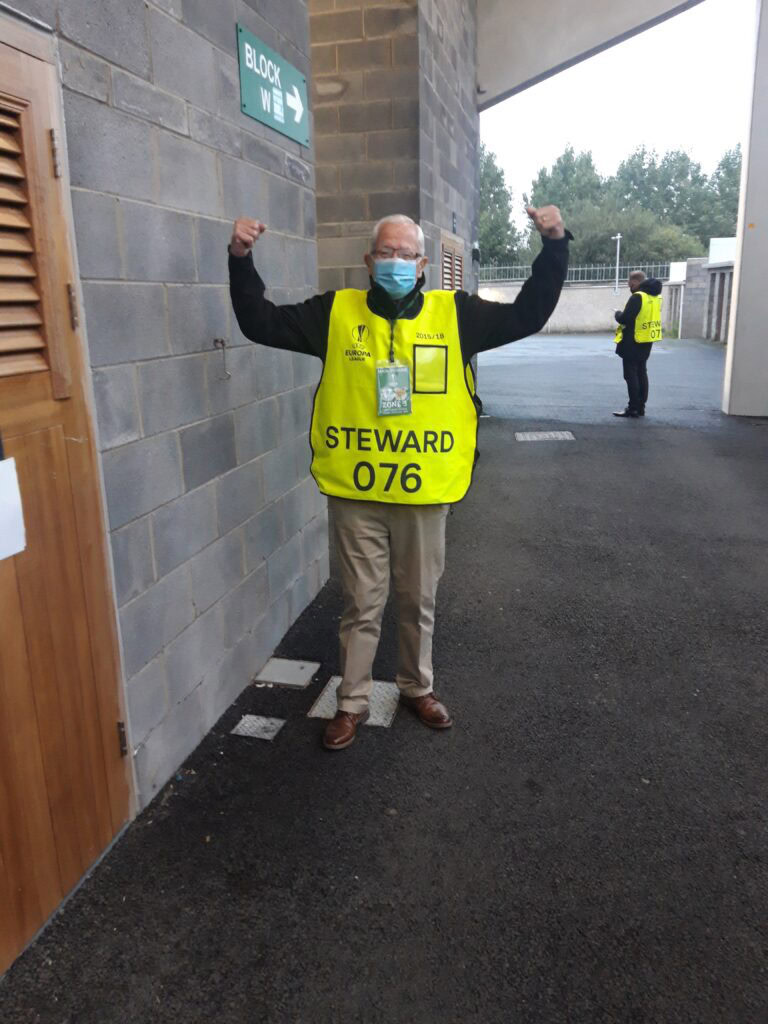 Stadium steward in high-visibility vest at Shamrock Rovers match, showing enthusiasm and team spirit.