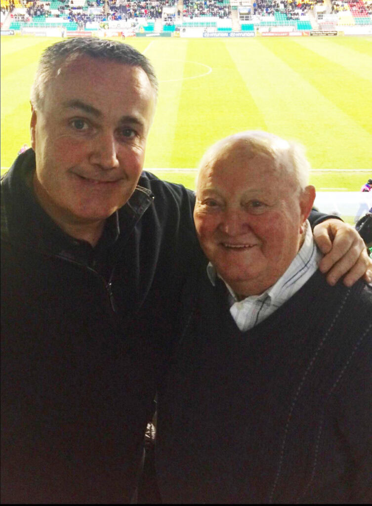 Two Shamrock Rovers supporters smiling at Tallaght Stadium during match.