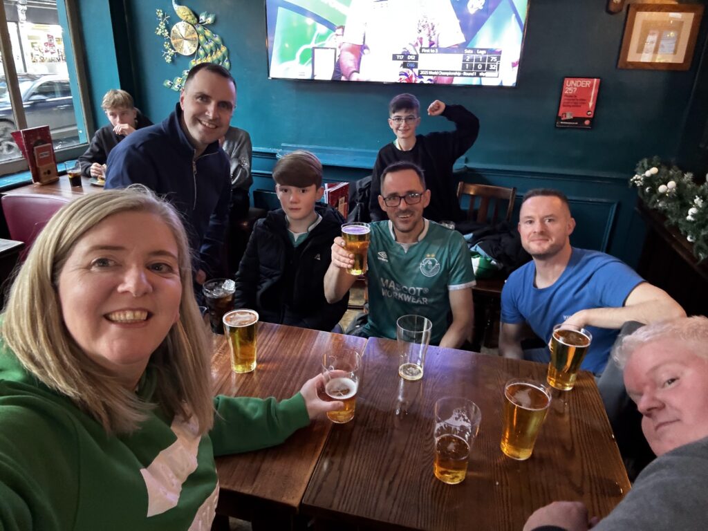 Group of Shamrock Rovers fans enjoying drinks at a pub after a match.