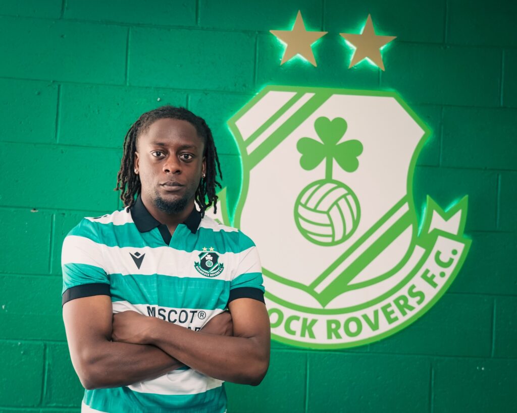 Shamrock Rovers football player standing in front of team logo.